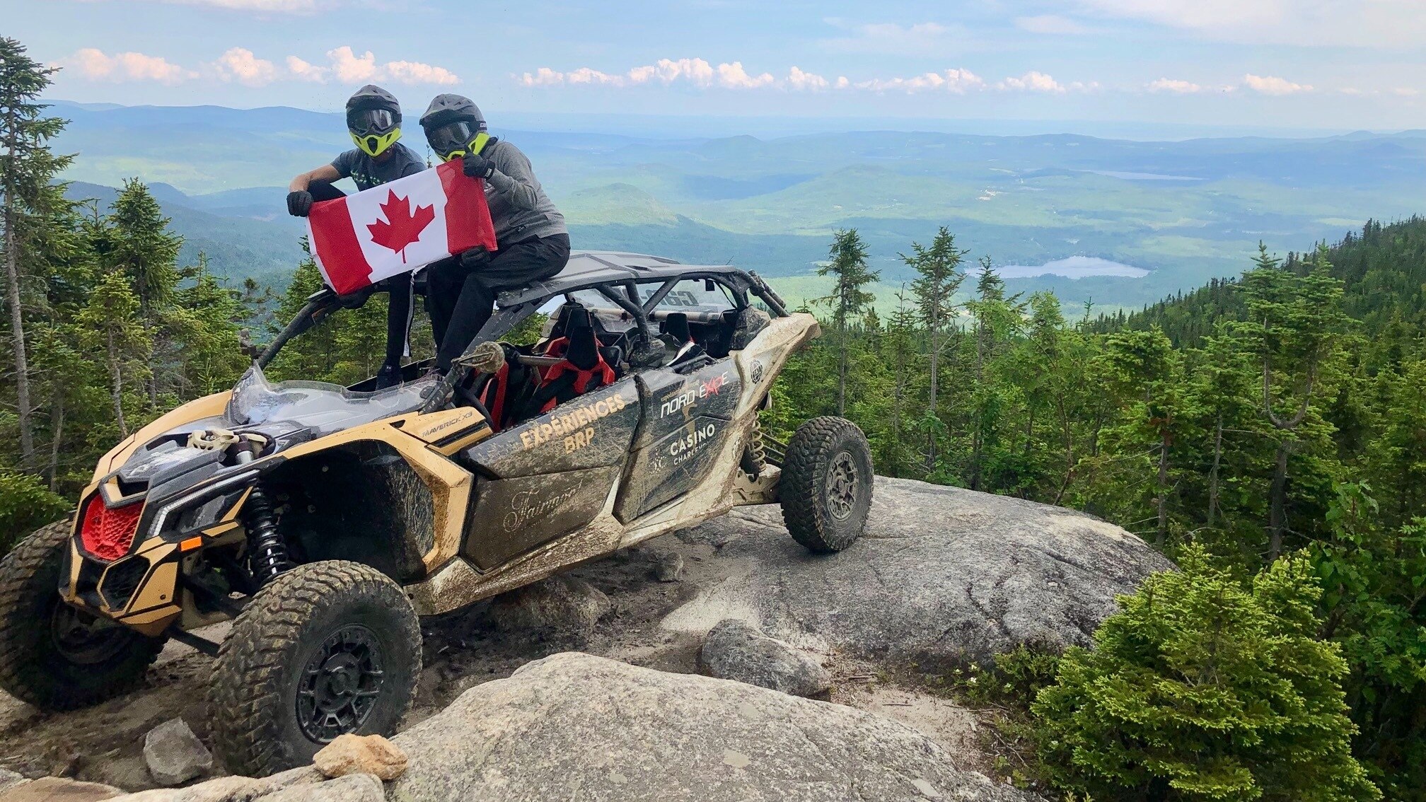 A unit parked on the top of a mountain with a Canadian flag and trees in the back 