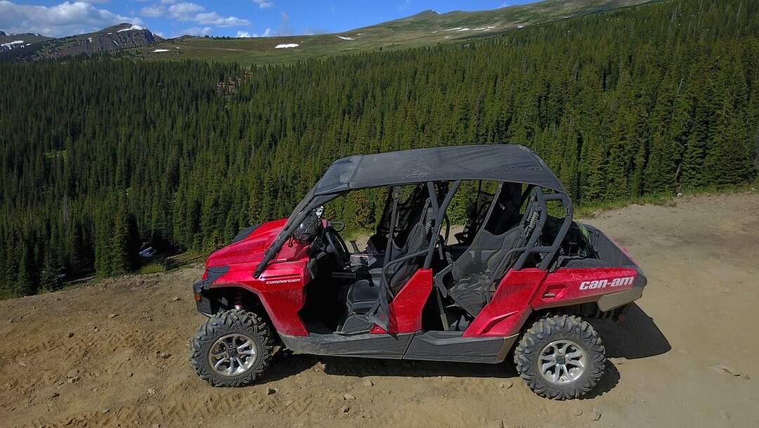 A red Can-Am unit parked with mountains and trees in the background